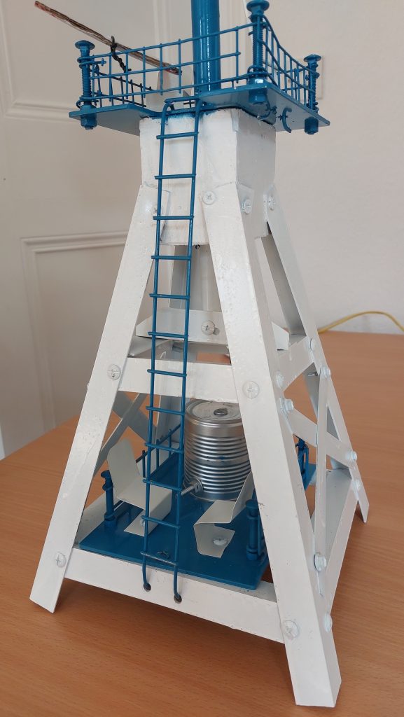 A model windmill with a white base, blue ladder and blue sails.