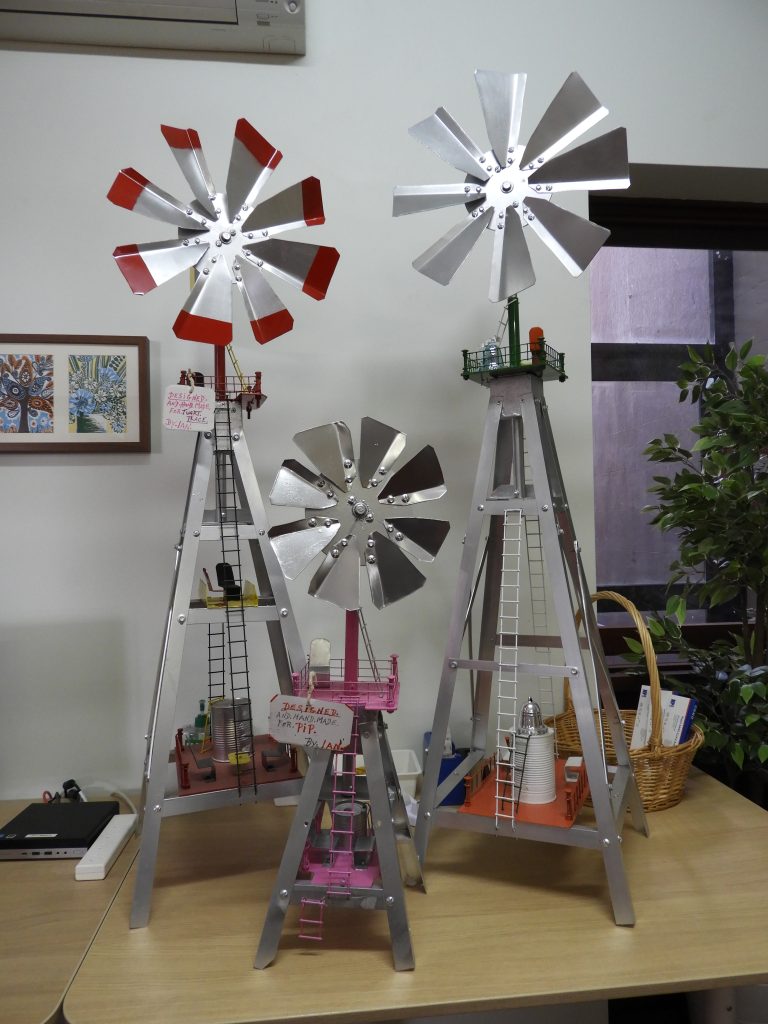 Three silver model windmills.