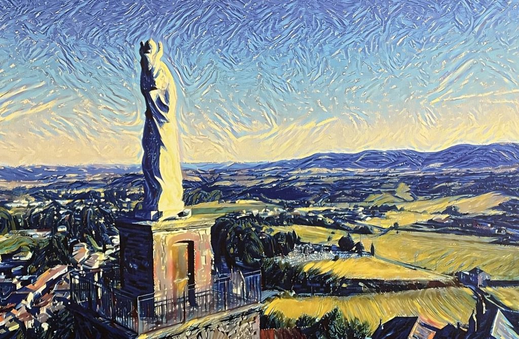 A statue of a figure overlooking green fields and a blue hill with a blue and yellow sky. Notre Dame de Camarès in the Sud Aveyron, France.