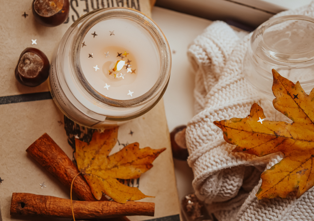 A candle with dried leaves beside it.